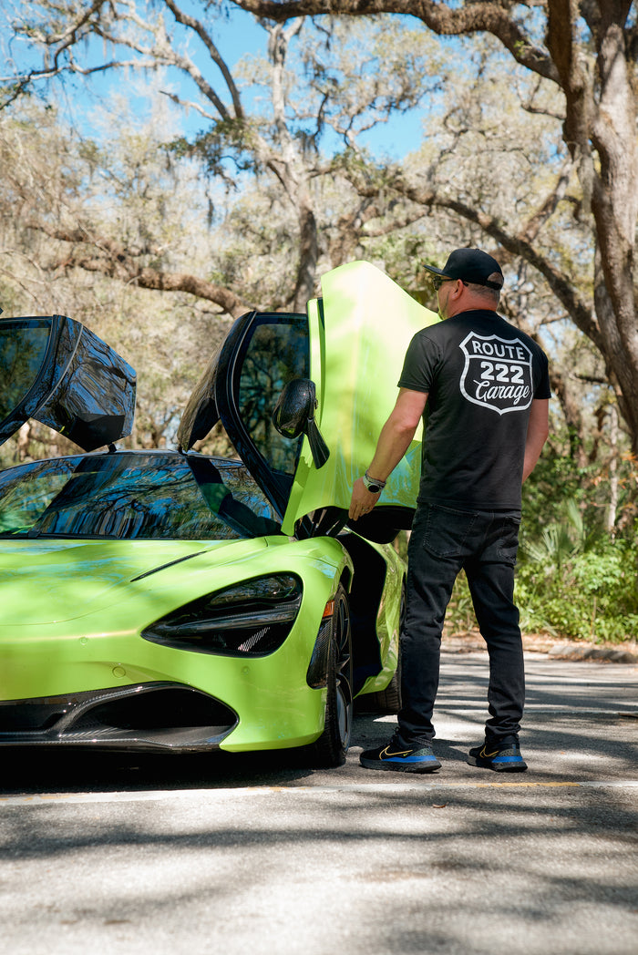 A Route 222 Garage shirt worn beside a green McLaren with its door open