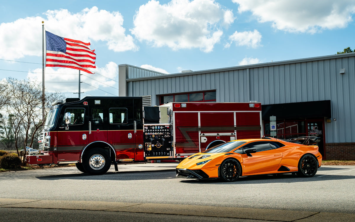 Orange Lamborghini Huracán STO parked beside a red fire truck outside the garage